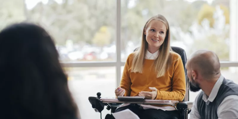 A woman in a wheelchair sitting in front of a group of people.