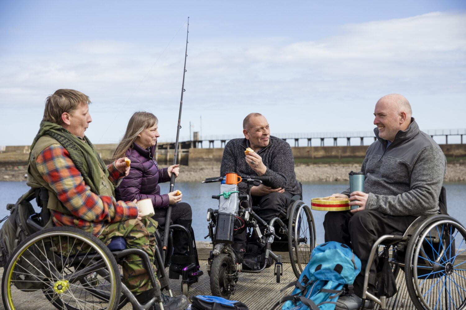 A group of people in wheelchairs sitting on a pier.