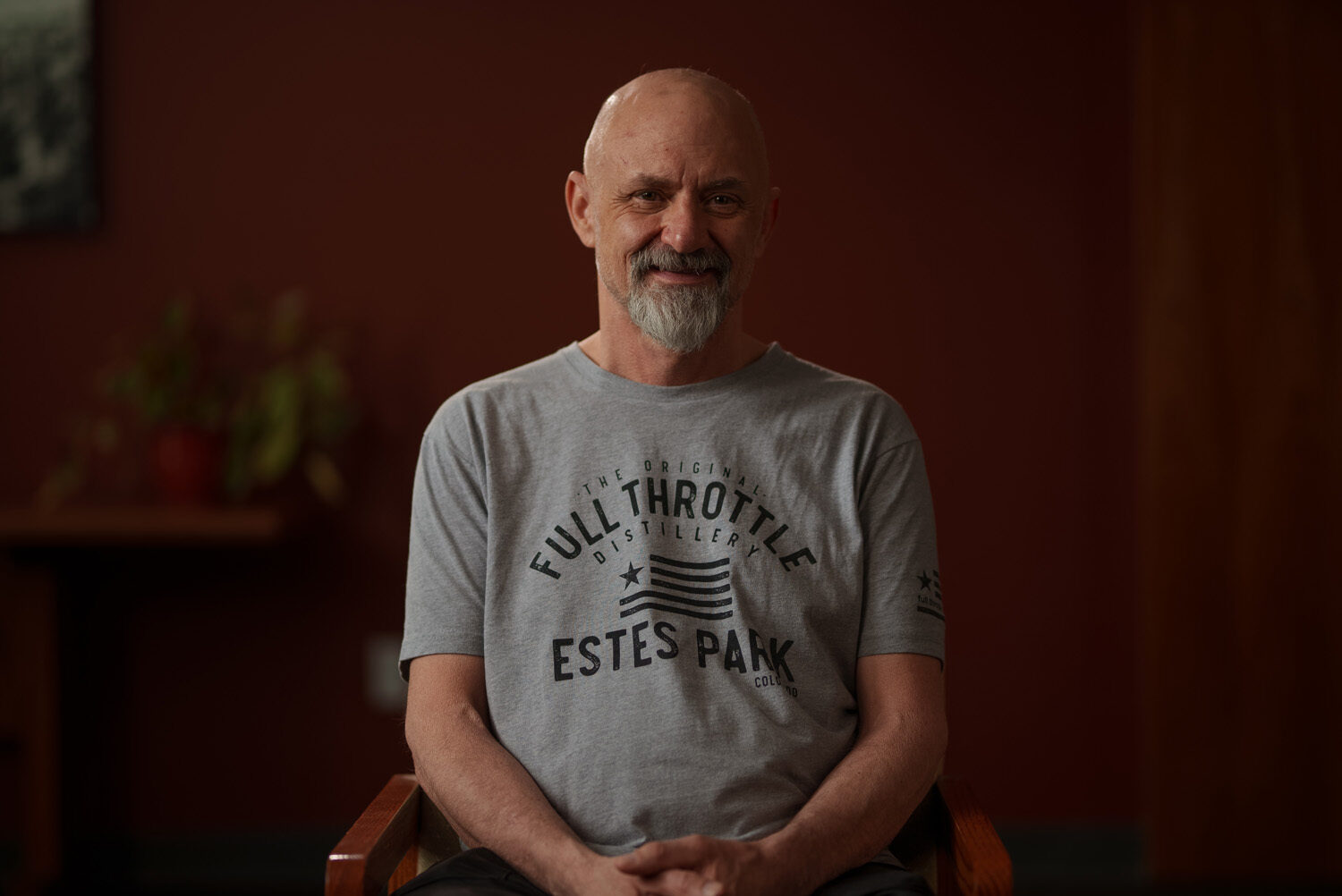 A man sitting in a chair wearing a grey t - shirt. profile picture