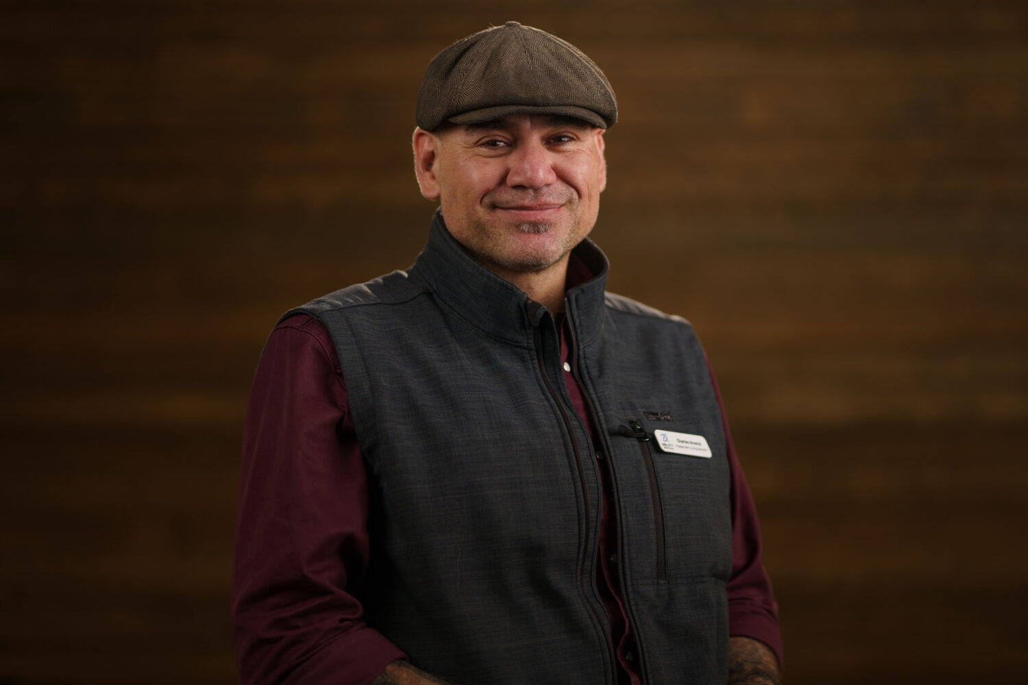 A man wearing a vest and hat smiles for the camera. profile picture