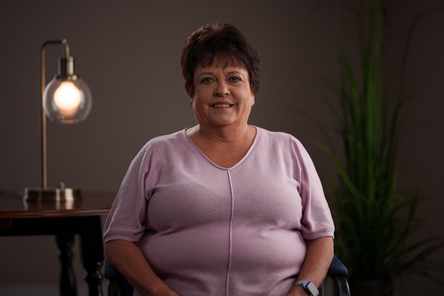 A woman sitting in a wheelchair in front of a lamp. profile picture