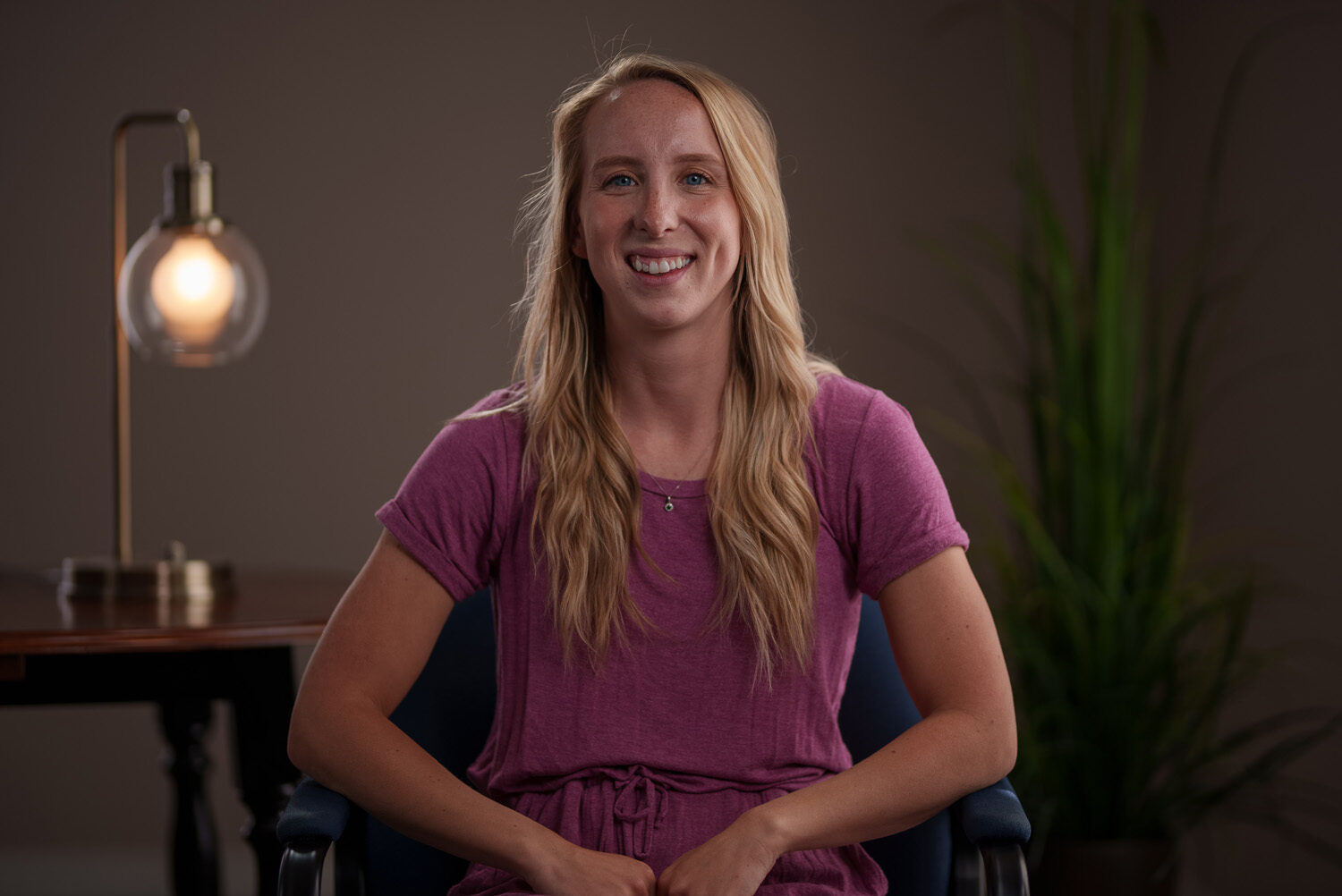A young woman in a purple shirt sitting in a chair. profile picture