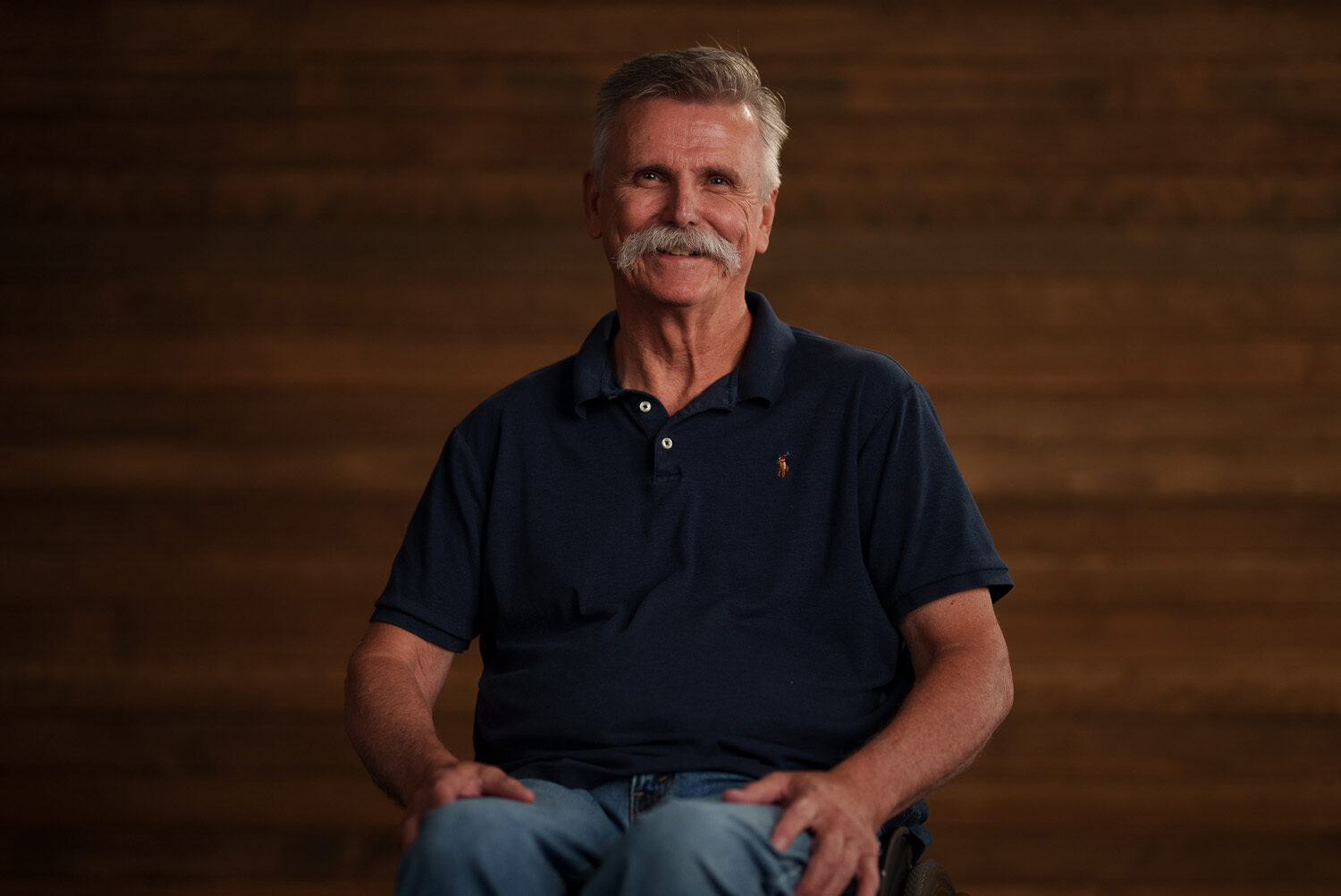 A man sitting in a chair with a mustache. profile picture
