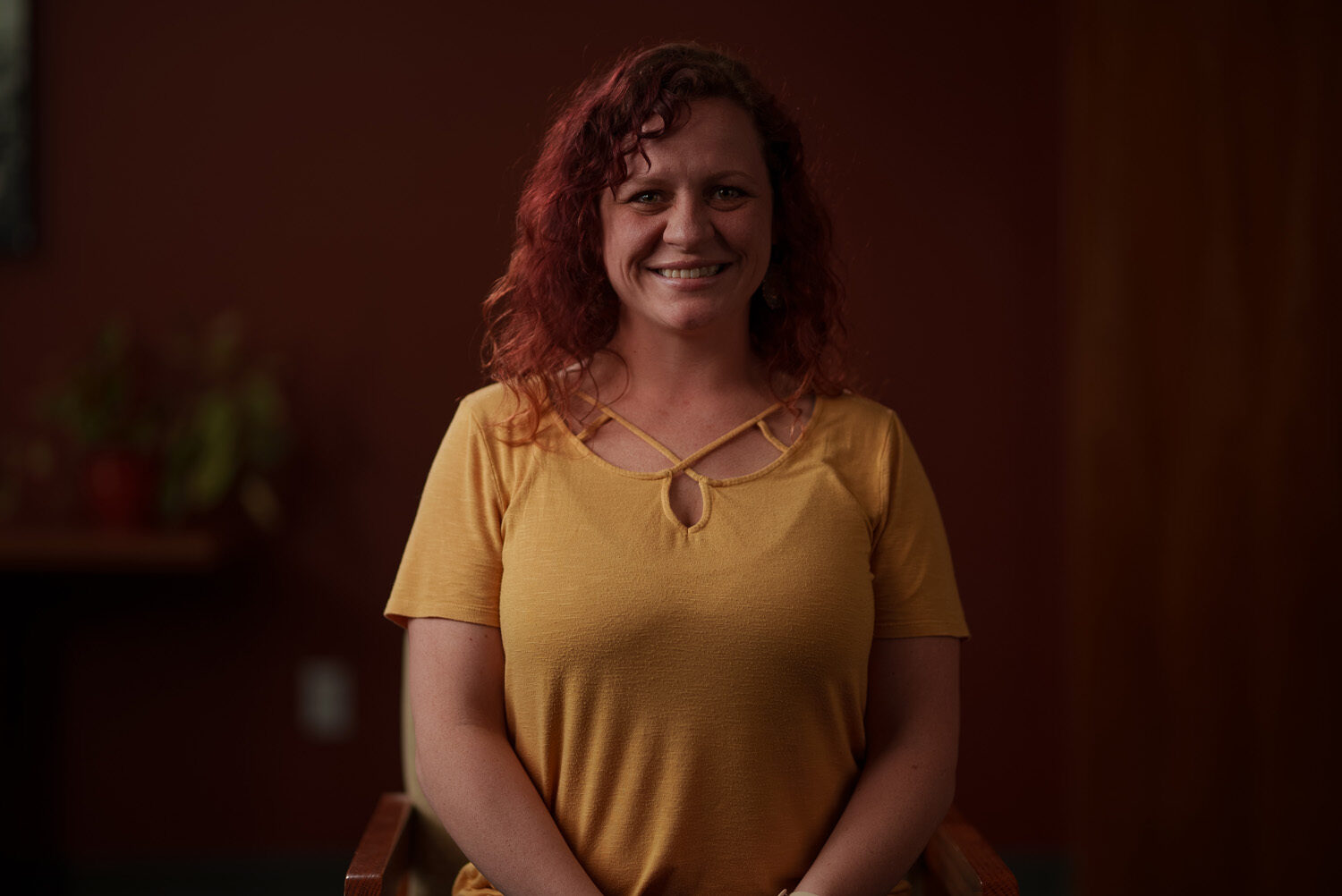 A woman in a yellow shirt sitting in a chair. profile picture